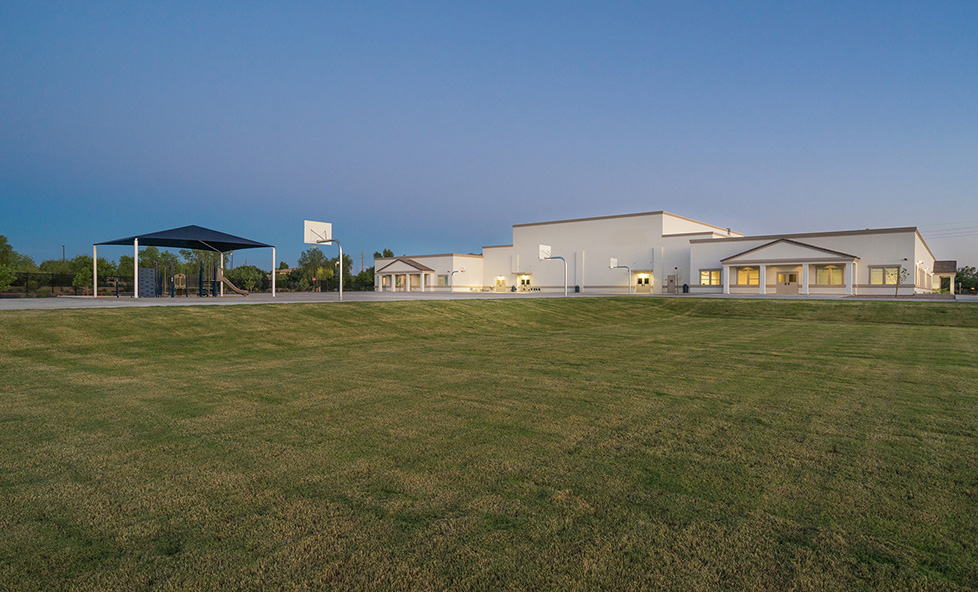 image taken down a field with a white school in the distance.