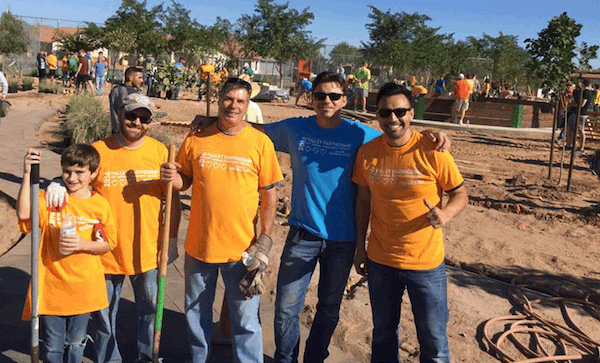 EPS Group Employees wearing orange and blue shirts doing landscape work with shovels at a local park.