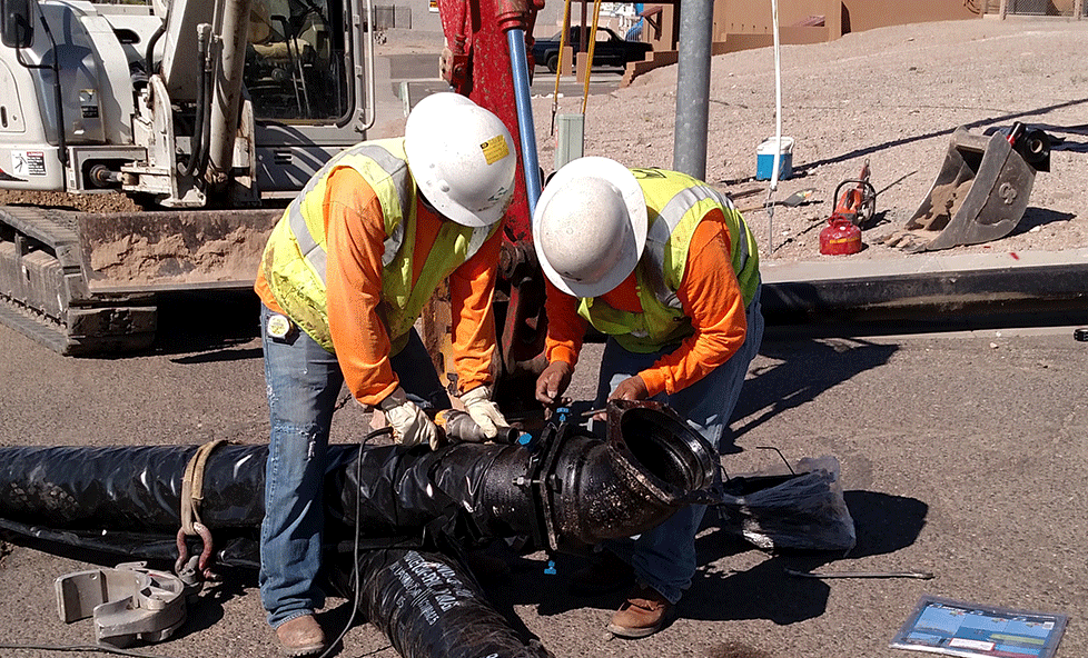 Two construction workers fixing a water line.