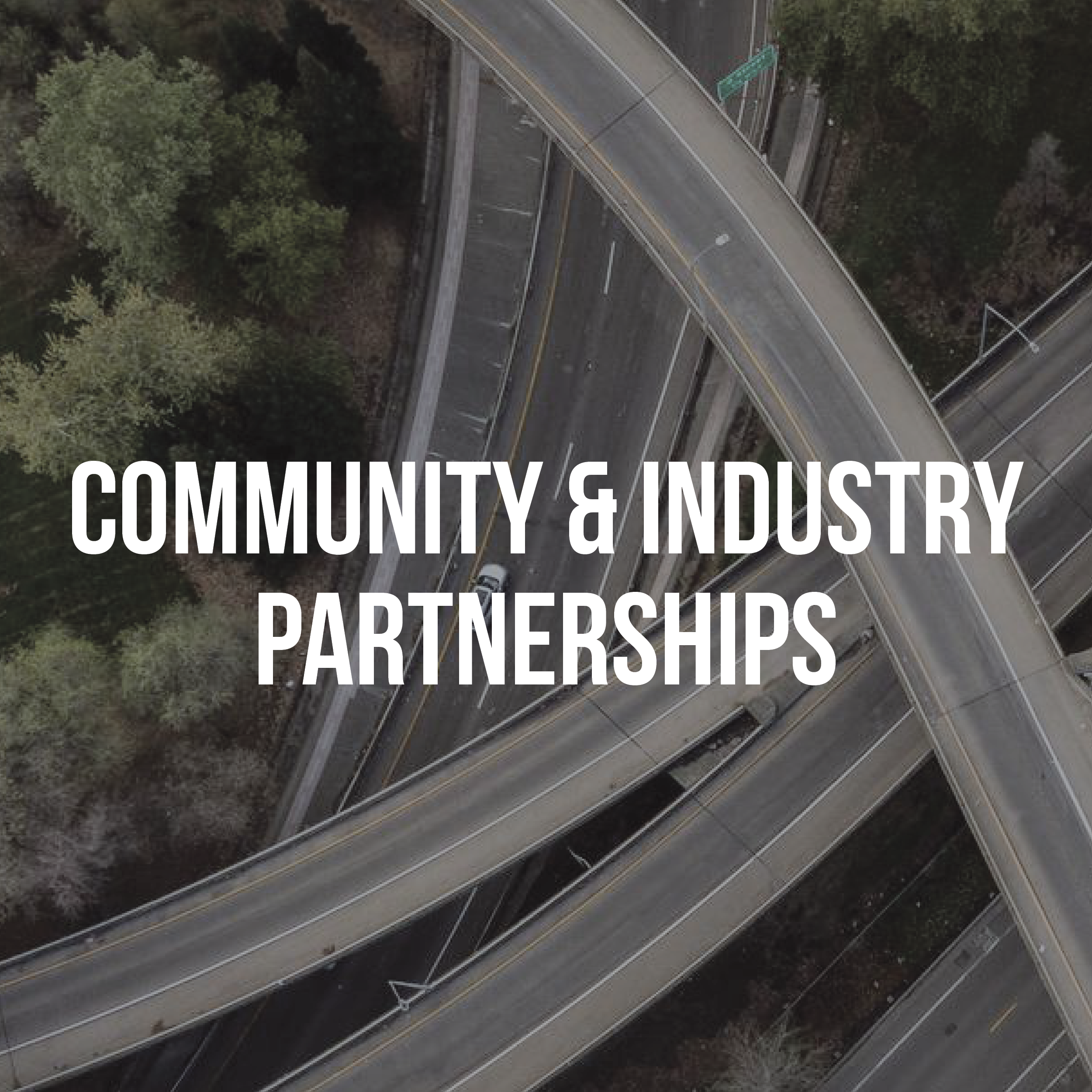 A faded picture of a birds-eye view of multiple freeway ramps in the background with white text on top that says “COMMUNITY & INDUSTRY PARTNERSHIPS”.