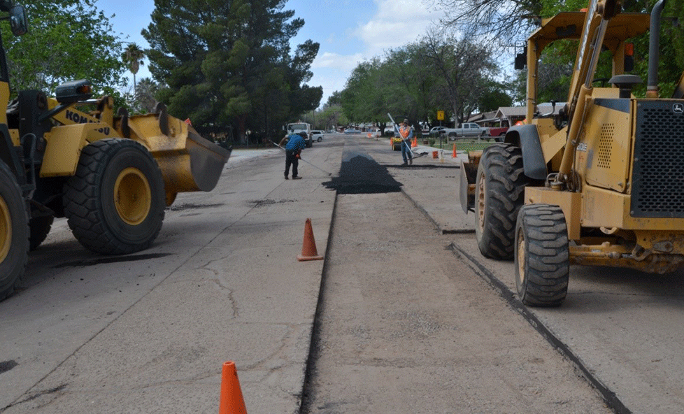 Construction vehicles and workers filling in areas of the road that were cut for the new lines.