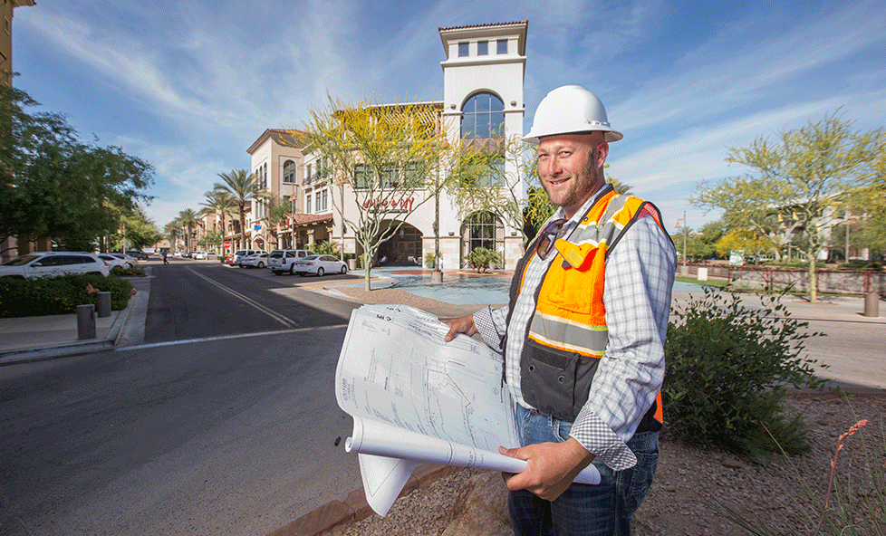 man in hardhat holding construction plans in front of Scottsdale Fashion Square