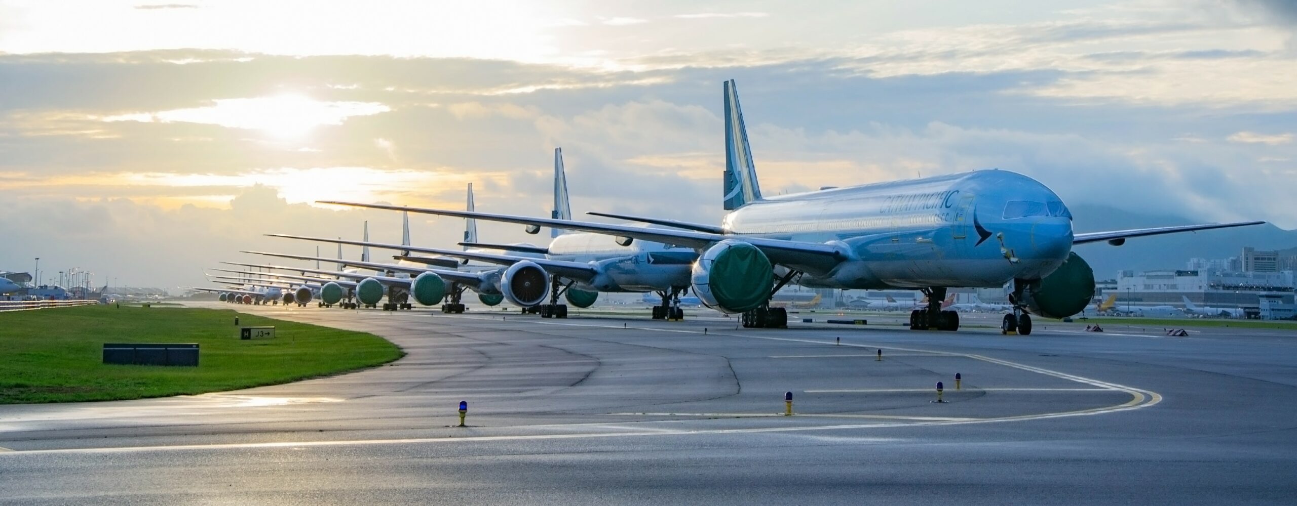 A queue of airplanes lined up on the tarmac of an airport.