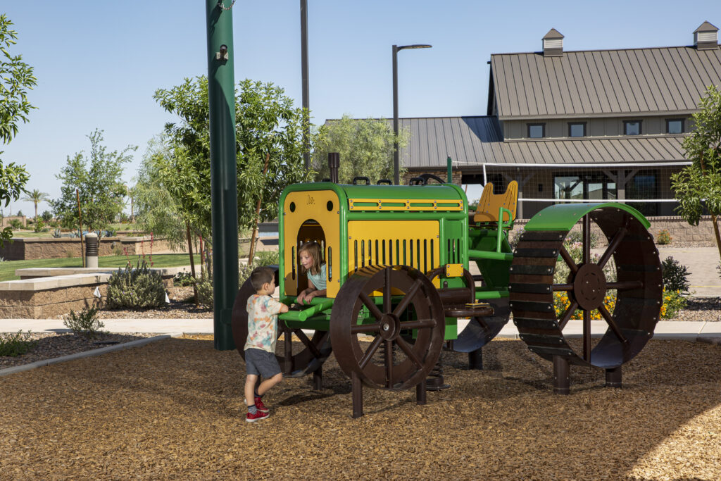 photo of two kids playing on the tractor (play obstacle) in the tot lot.